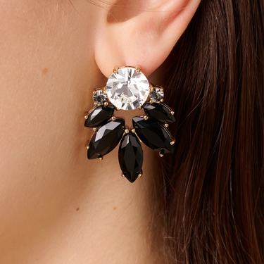 Close-up of an earring with a large central gemstone and black stones on a person's ear.