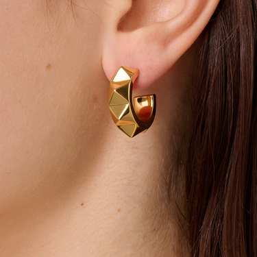 Gold geometric earring worn by a person