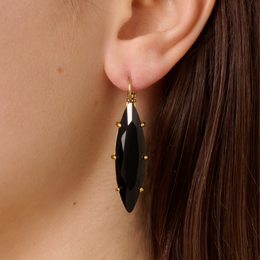 Black earrings with gold accents worn by a person