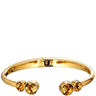 Gold-tone open cuff bracelet with three round amber-yellow crystal accents, shown on a plain white background.