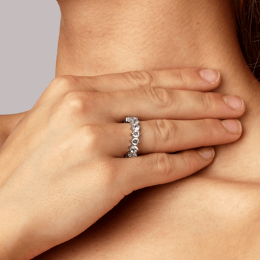 Close-up of a hand wearing a diamond ring on a neutral background