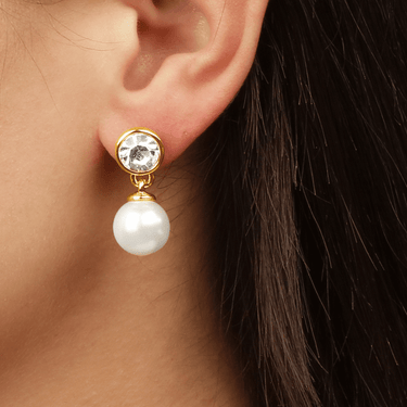 Pearl earring with gold setting worn by a person