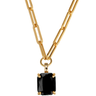 Gold chain necklace with a black pendant on a white background
