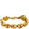 A gold-tone metal bracelet featuring oval faceted amber crystal rhinestones in bezel settings, with a lobster clasp closure, shown against a plain white background.