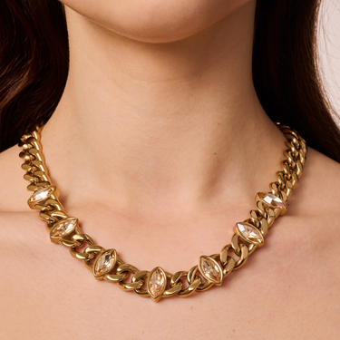 Gold chain necklace with clear gemstones worn by a person