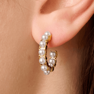 Pearl hoop earring worn on an ear with gold accents