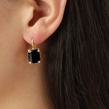 Black square gemstone earring on a person's ear with dark hair.