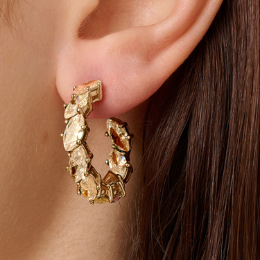Gold hoop earrings with gemstones worn by a person