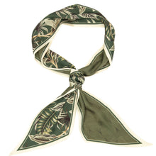 A silk scarf with a tropical leaf pattern in olive green, beige, and white, tied in a knot against a plain white background.