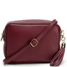 A burgundy pebbled leather crossbody bag with a matching leather tassel charm and gold-tone hardware, shown on a clean white background.