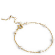 Gold bracelet with white beads on a white background