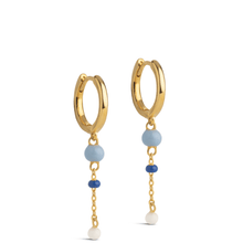 Gold hoop earrings with blue and white bead charms on a white background