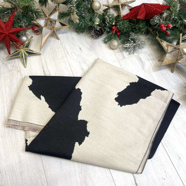 Black and white patterned blanket on a wooden surface with Christmas decorations.