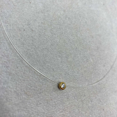 Gold necklace with a small round pendant on a light gray background