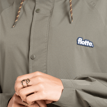Green jacket with 'flotte' logo and a person wearing rings.
