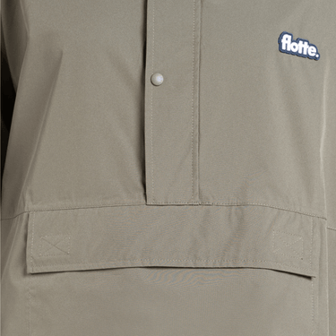 Close-up of a beige jacket with a button and 'flotte' logo on a gray background