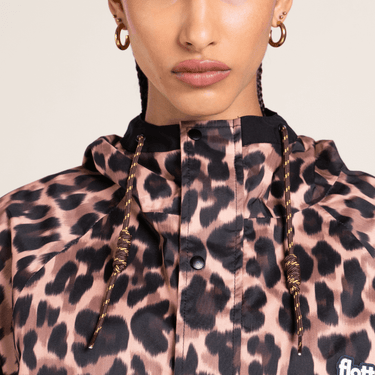 Person wearing a leopard print jacket with gold accents on a plain background