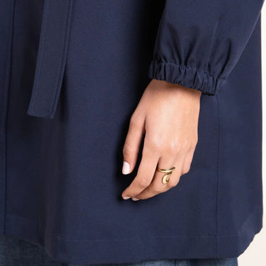 Navy blue coat with a hand wearing a gold ring on a white background
