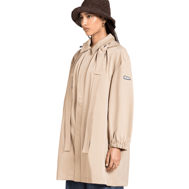 Person wearing a beige raincoat with a brand logo on a white background