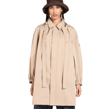Person wearing a beige trench coat on a white background