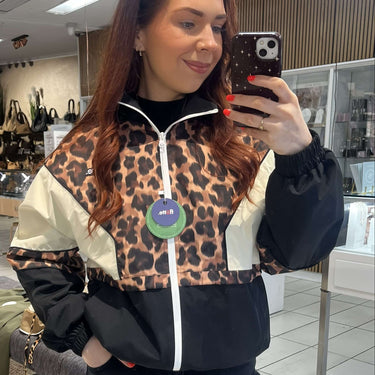 Person wearing a leopard print jacket with a store interior in the background