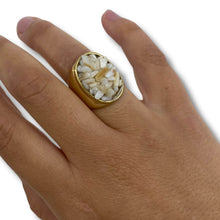 Gold ring with a stone on a hand against a white background