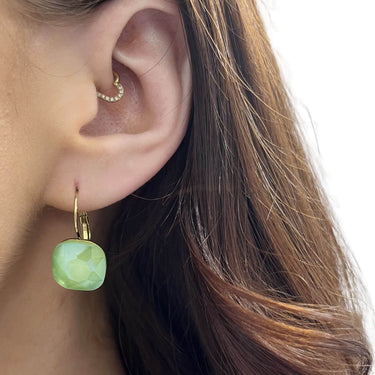 Close-up of a person wearing a green earring with gold hoop.