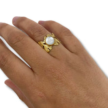 Gold ring with a white stone on a hand against a white background