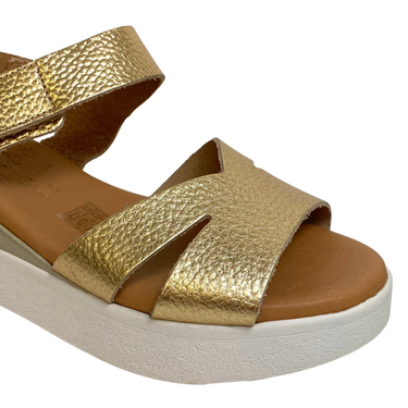 Gold sandal with a white sole on a white background