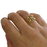 Gold ring with intricate design on a person's finger against a white background