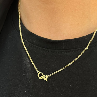 Gold necklace with a small pendant on a black shirt