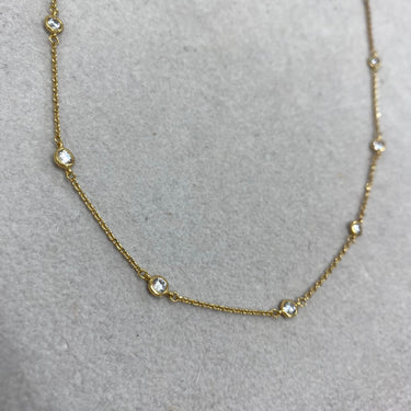 Gold necklace with small diamonds on a gray background