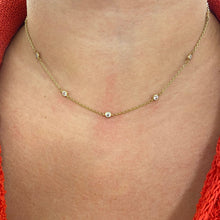 Gold necklace with small beads on a person wearing a red garment