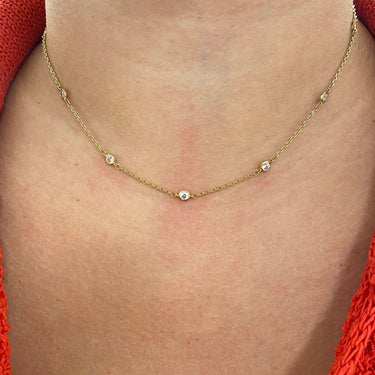 Gold necklace with small beads on a person wearing a red garment