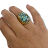 Hand wearing a ring with a green gemstone on a white background