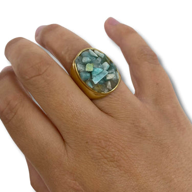 Hand wearing a ring with a green gemstone on a white background