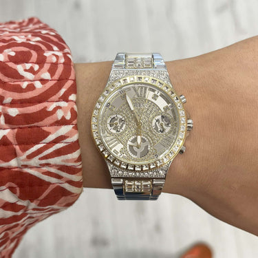 Silver watch on a wrist with a colorful patterned cuff against a light background