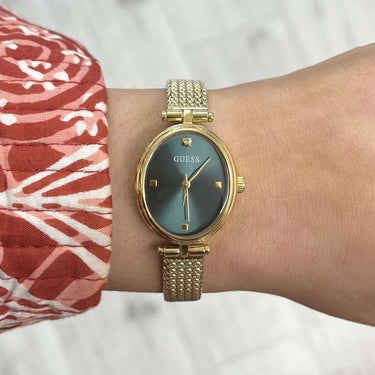 Gold watch on a wrist with a colorful fabric background