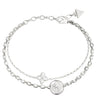 A silver-toned double-strand chain bracelet featuring a circular medallion, a four-petal floral charm, and a triangular logo tag on the clasp, set against a plain white background.