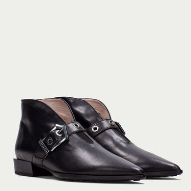 Black leather boots with a decorative buckle on a light gray background