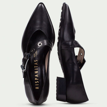 Black pointed-toe shoes with strap details on a light gray background
