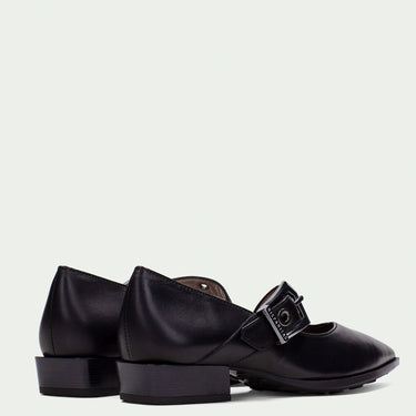 Black leather shoes with buckles on a light gray background