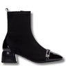 A black ankle boot with a black patent leather pointed toe and a silver-tone decorative buckle detail on the vamp, shown against a plain white background.