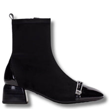 A black ankle boot with a black patent leather pointed toe and a silver-tone decorative buckle detail on the vamp, shown against a plain white background.