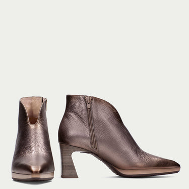 Pair of brown ankle boots with pointed toes on a light beige background