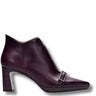 A dark plum purple leather ankle boot with a pointed toe, a chunky block heel, and a decorative silver buckle detail on the side, shown against a plain white background.