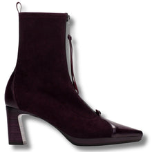 A dark plum purple suede ankle boot with a pointed toe, a chunky block heel, and a side zipper with a tassel pull, shown against a plain white background.