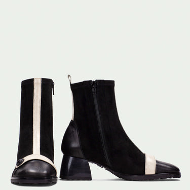 Black ankle boots with white stripes on a light gray background
