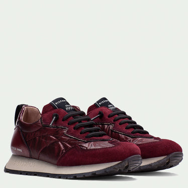 Pair of maroon sneakers with black laces on a light gray background
