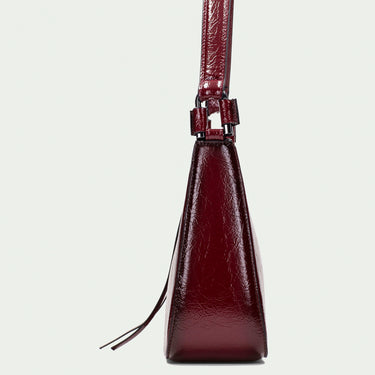 Burgundy handbag with a strap on a light gray background